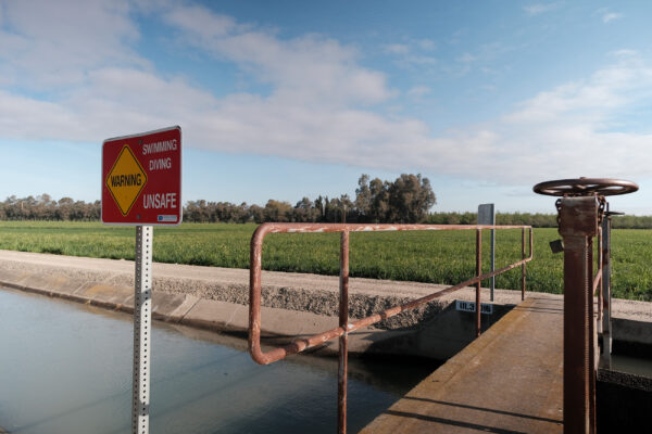 Walking bridge over irrigation canal with Warning sign that reads "swimming, diving unsafe."