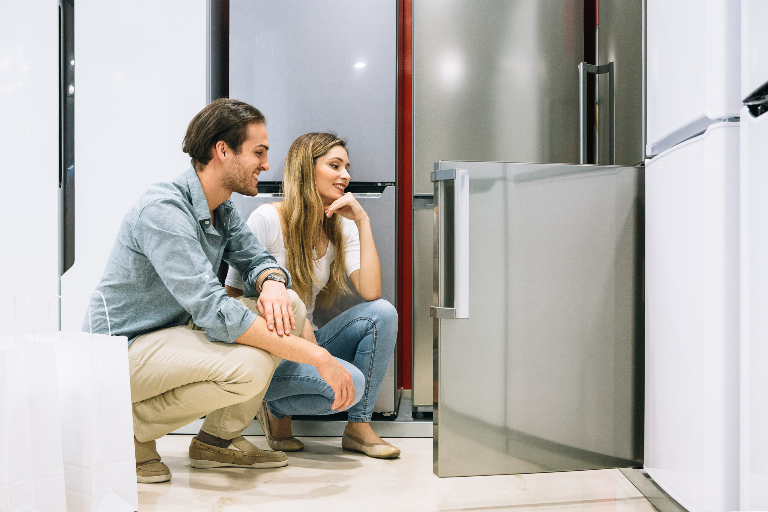 Young man and woman choose a fridge in an appliance shop