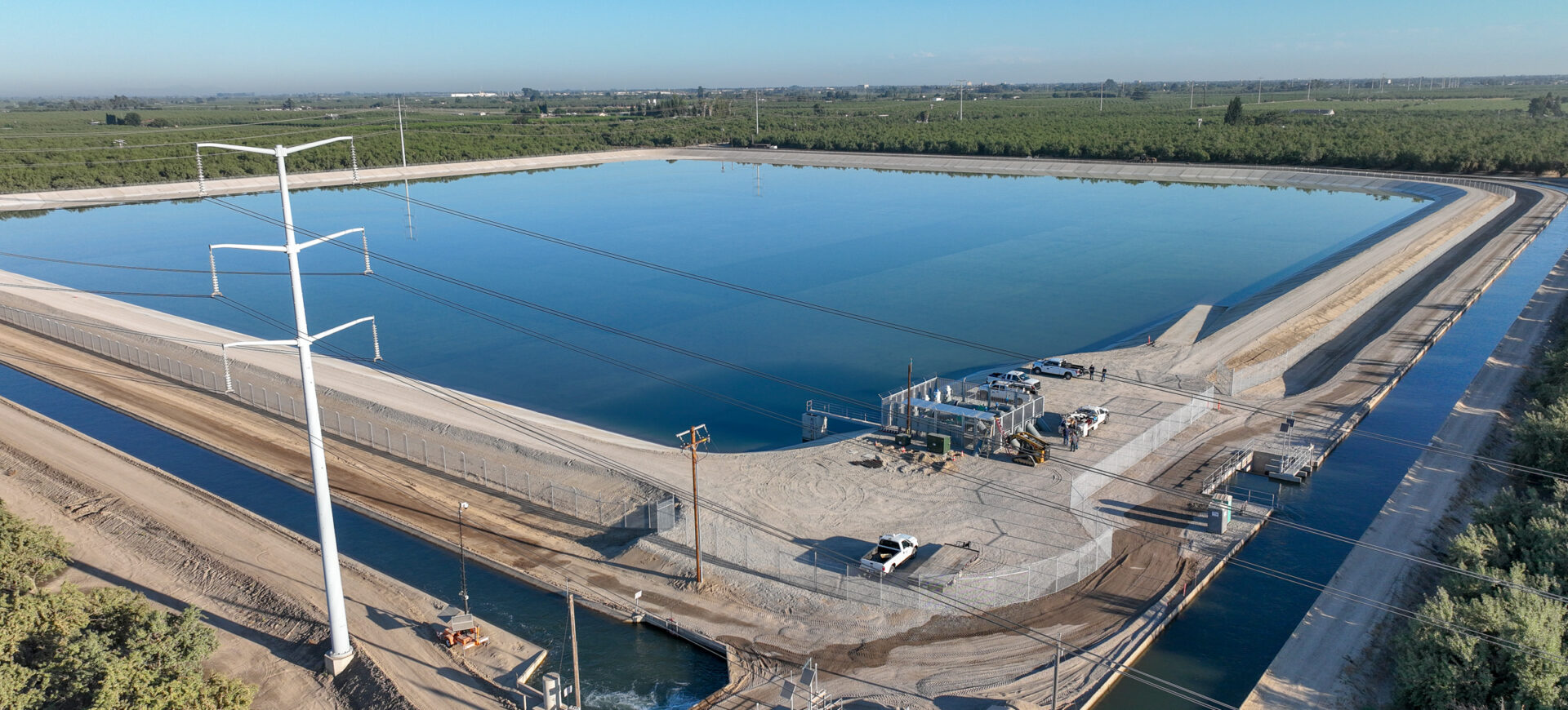 Aerial photo of a small reservoir surrounded by canals and orchards.