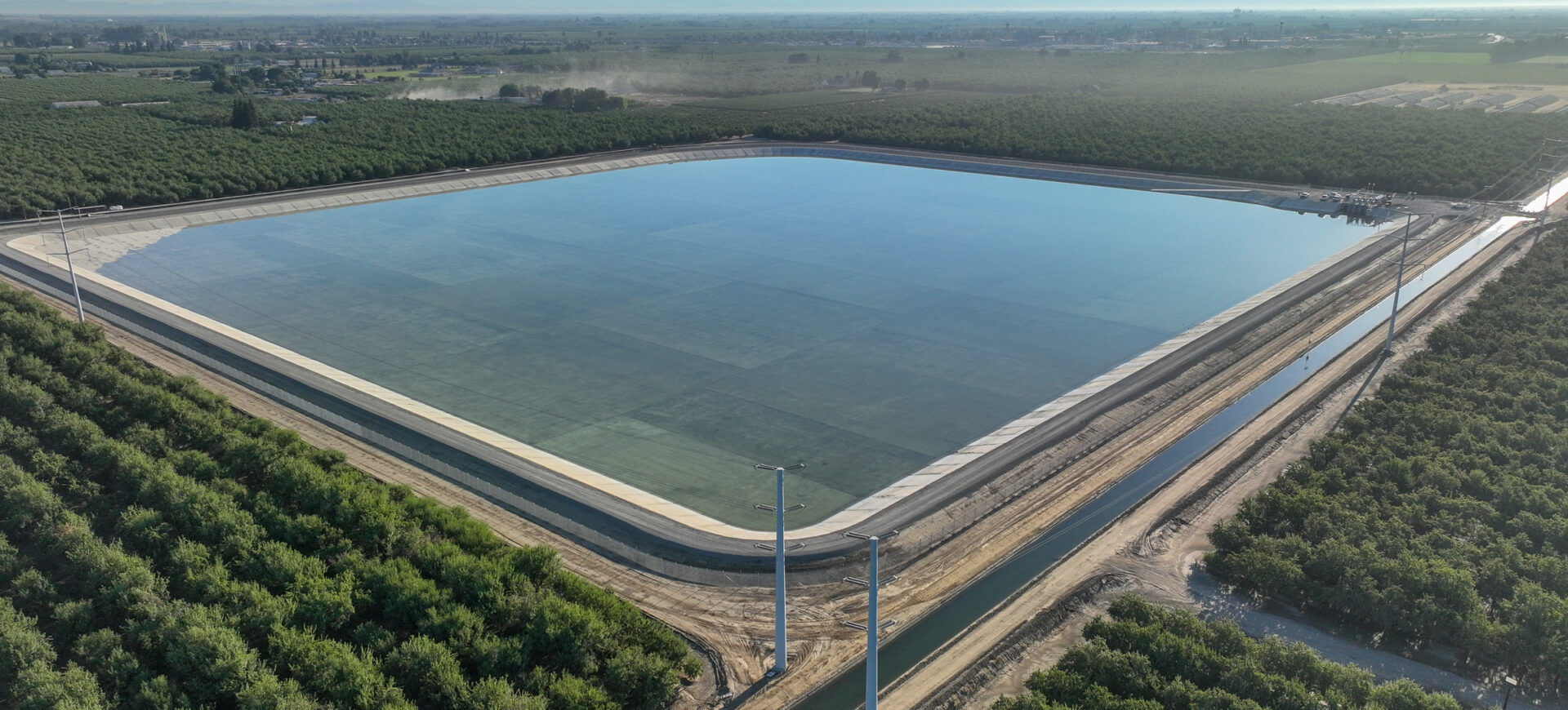 Aerial photo of a small reservoir surrounded by canals and orchards.