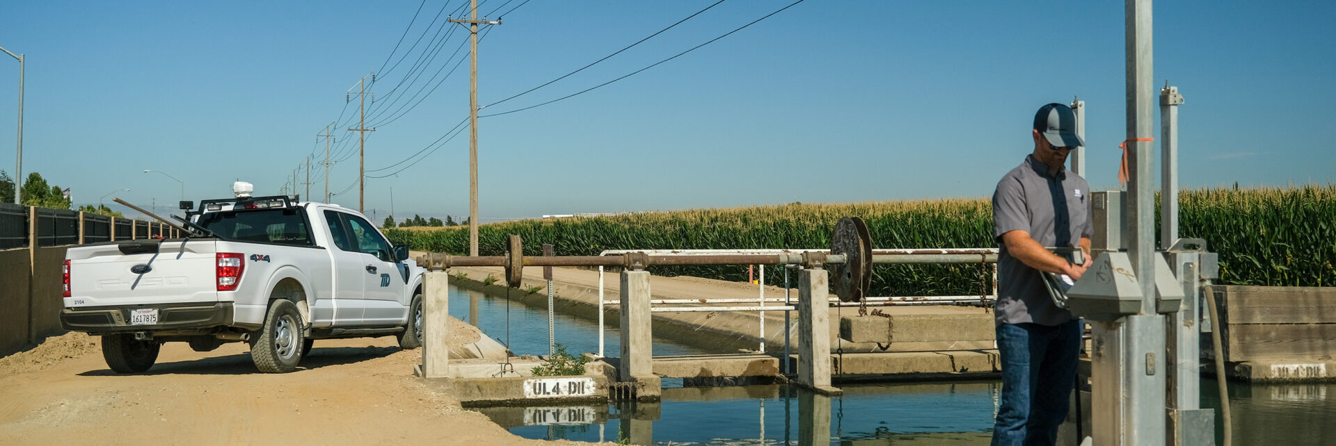 Water distribution operator operates rubicon gate along irrigation canal.